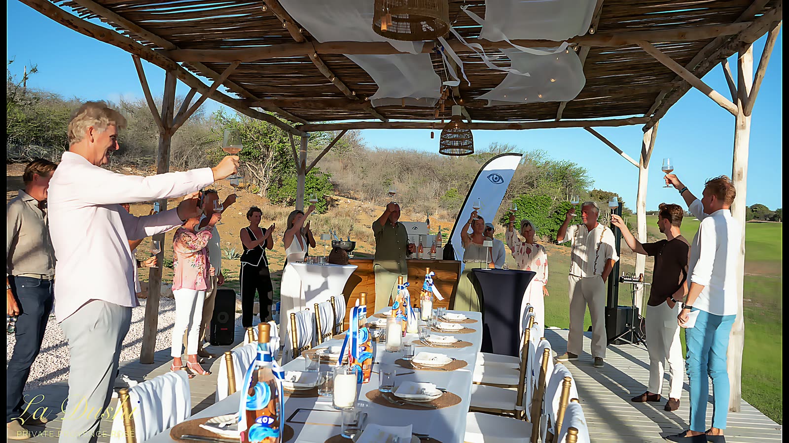 Guests raising a glass around the table as the light drops.